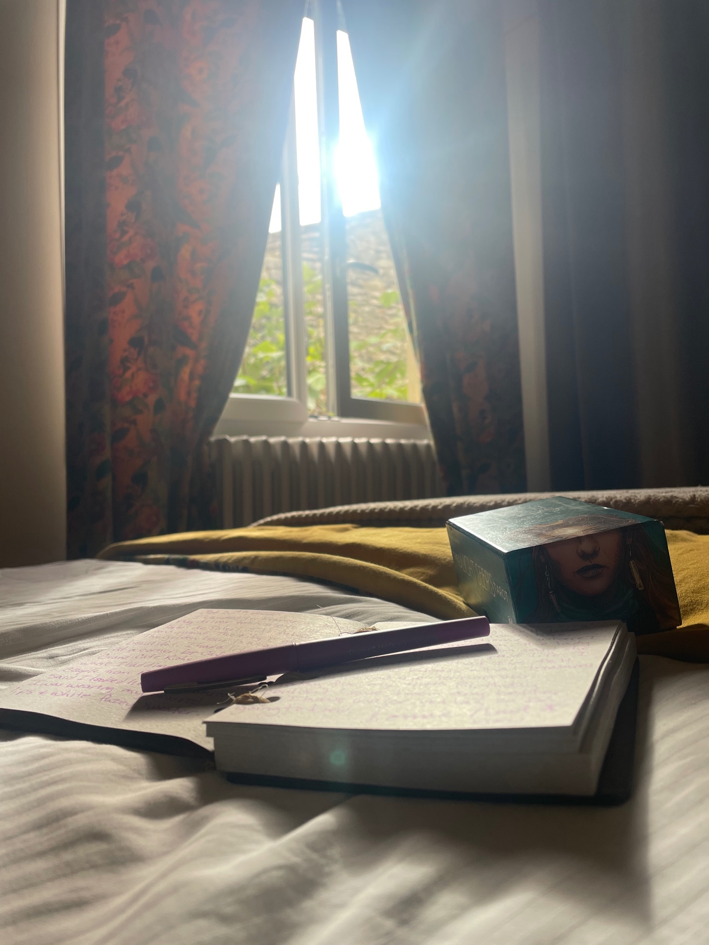A journal and book resting on sunlit linen with morning light through a window